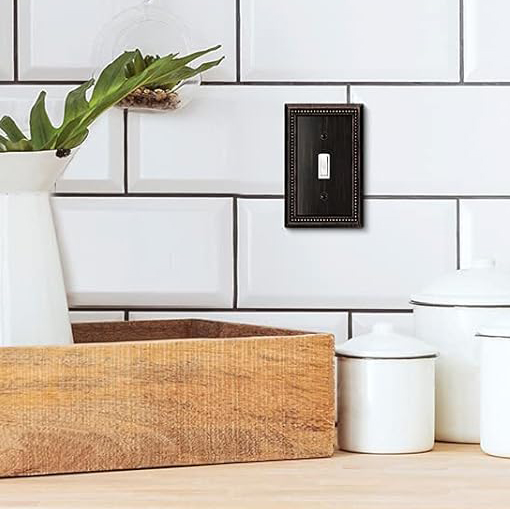 Close up of white tiled kitchen wall with decorative switch plate